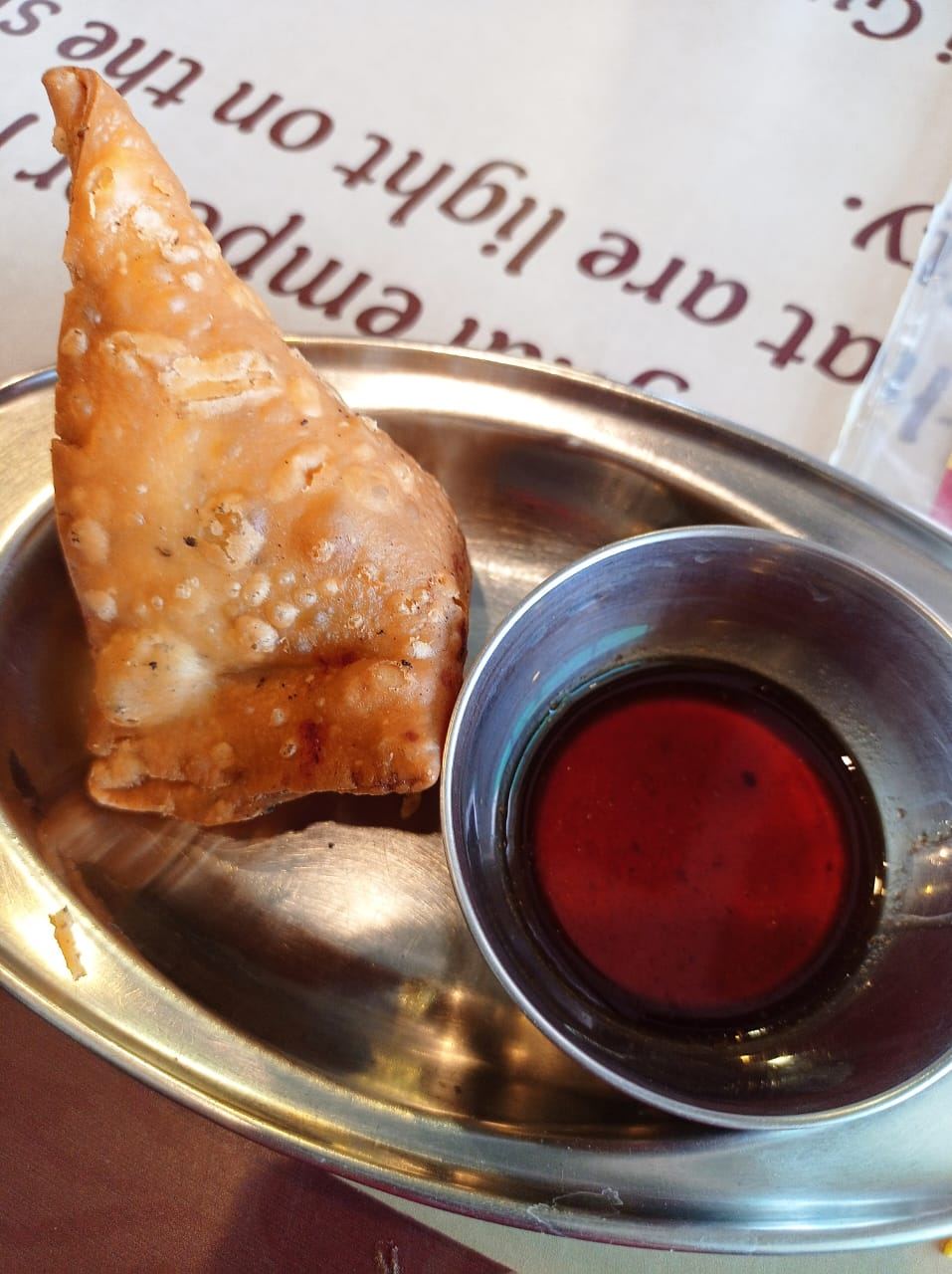 Golden fried samosas with chutney on a steel tray
